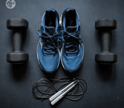 Training shoes, dumbbells, and a jump rope on an exercise mat