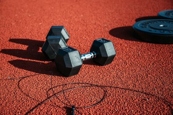 Dumbbells and a jump rope on a red training surface