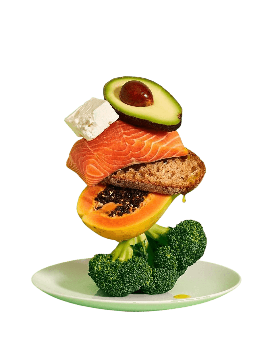 A stack of salmon, avocado, feta, bread, papaya and broccoli on a plate